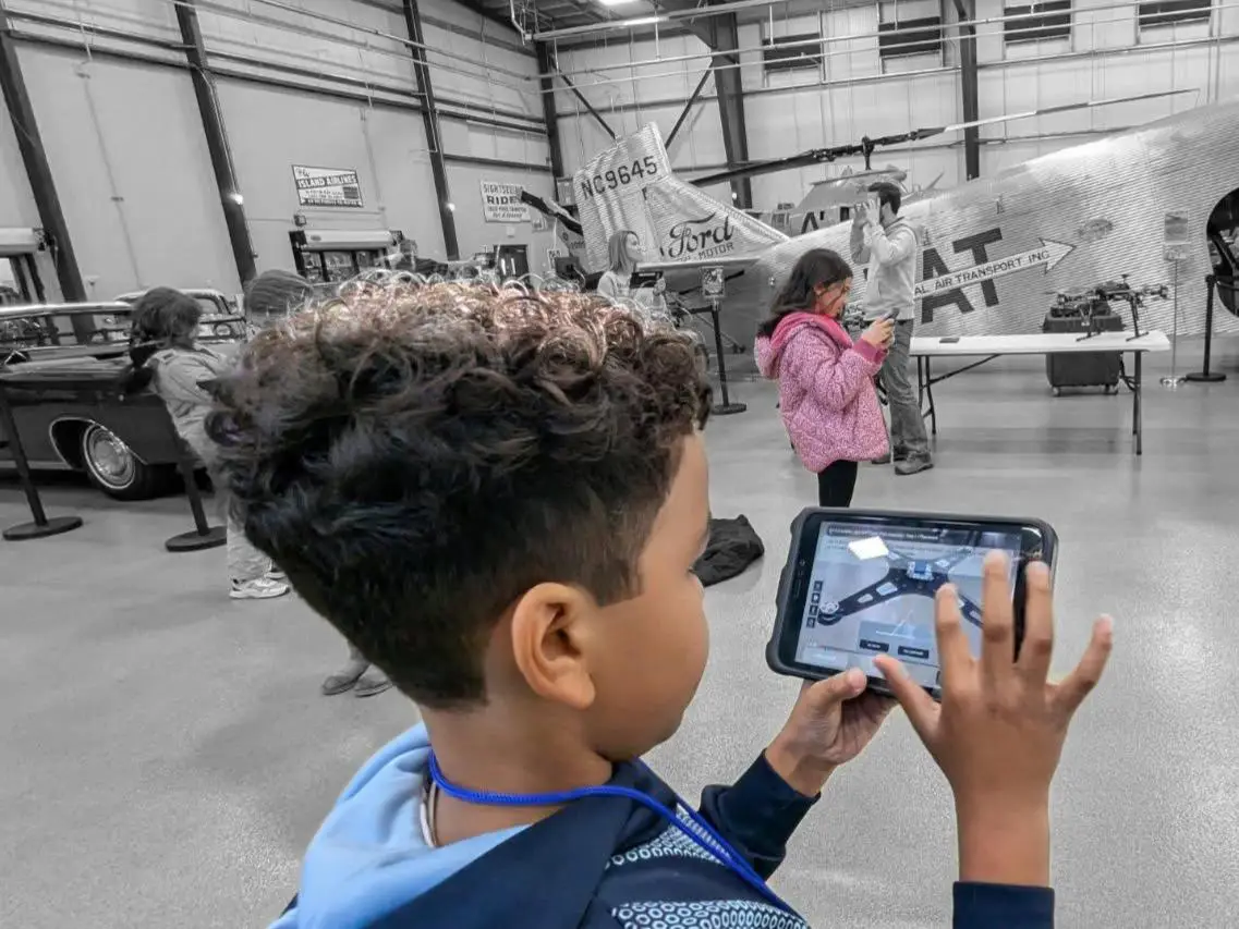 Child at the airspace museum operating a drone using a mobile phone